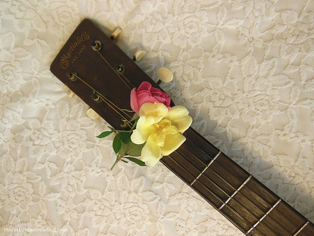 Roses resting on the neck of a guitar