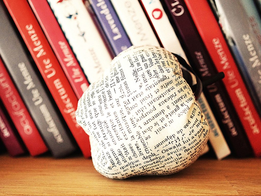 A paper apple in front of books on a shelf