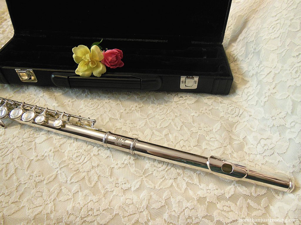 A flute next to a flute case with roses in it