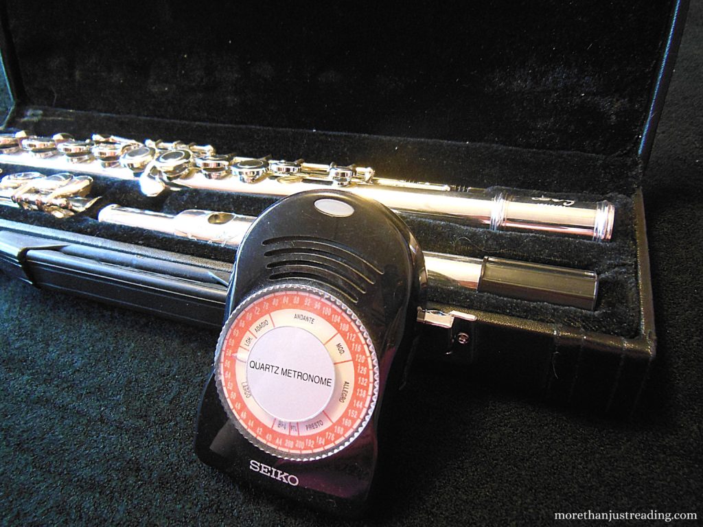 A metronome leaning against a flute case with a flute in it