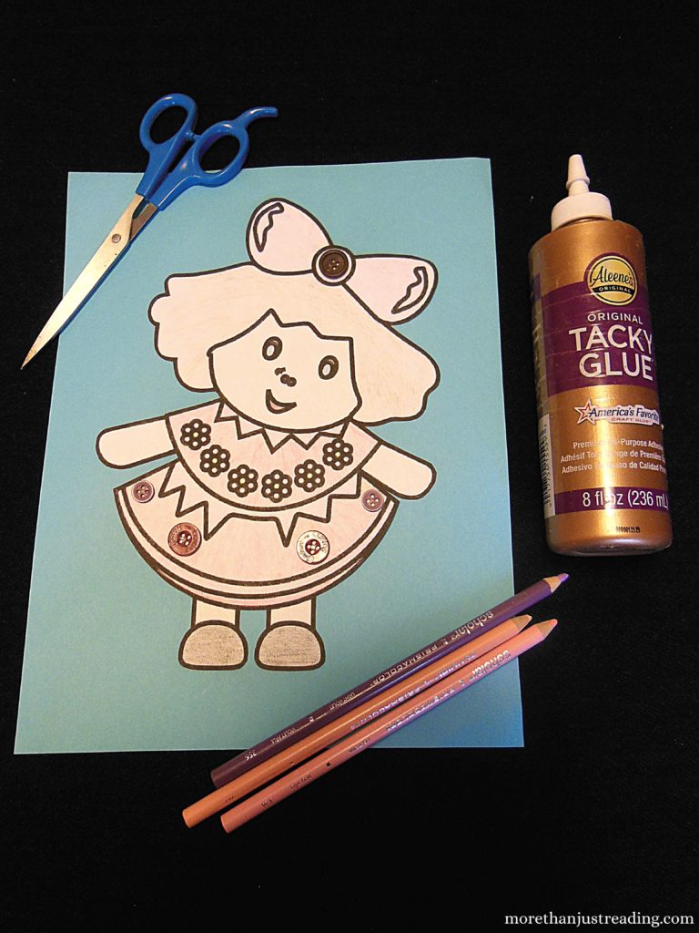 A doll craft with scissors, colored pencils, and glue